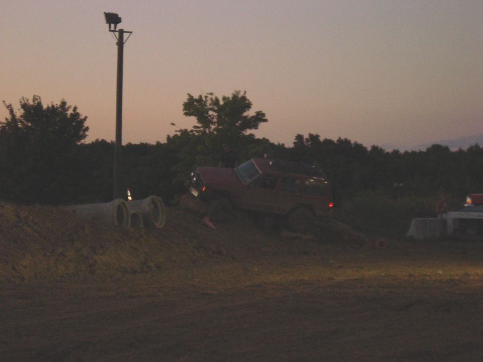 Red SUV on a dirt incline with a pole and lights in the background