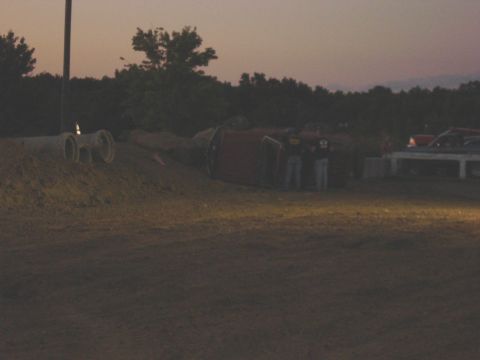 1994 Ford Bronco - A vehicle has overturned on a dirt embankment near concrete pipes at dusk.