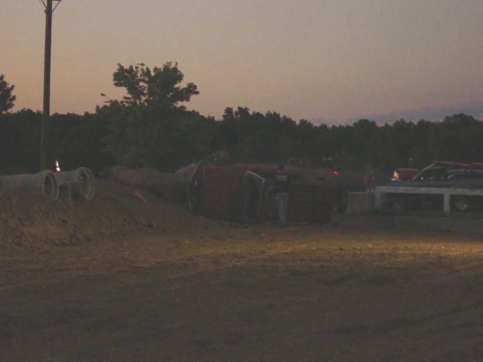 Red SUV rolled onto its side, with a flatbed truck nearby