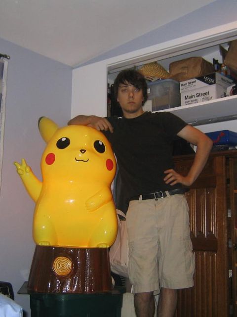 1969 Ford Mustang - A man poses with a large Pikachu statue in a room filled with storage items.