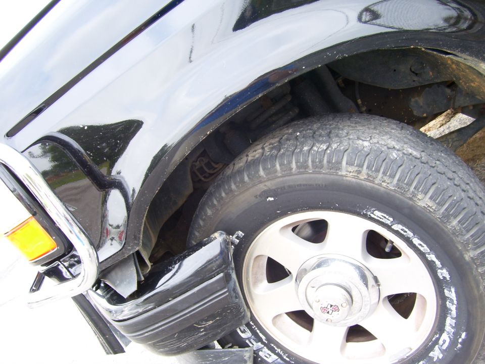 Front wheel well of a black truck showing a Sport tire on a silver alloy wheel