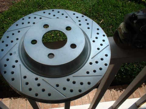 1969 Ford Mustang - A close-up view of a slotted and drilled brake rotor and caliper, likely an aftermarket upgrade for improved performance.