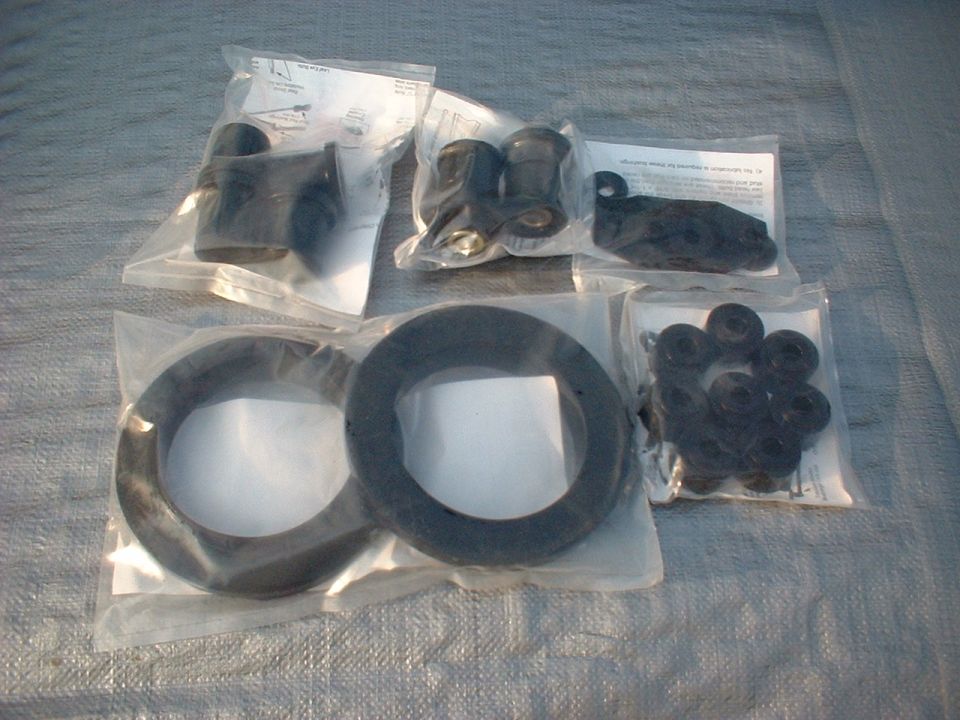 Several plastic-wrapped automotive rubber parts, including two large rings and a bag of smaller grommets, laid out on a grey tarp