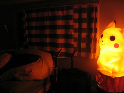 1969 Ford Mustang - A bright Pikachu lamp illuminates a room containing two guitars and a bed, with striped curtains in the background.