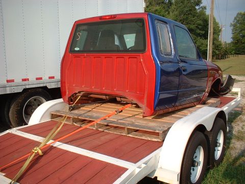1999 Ford Ranger - A two-tone red and blue truck cab is transported on a flatbed trailer.