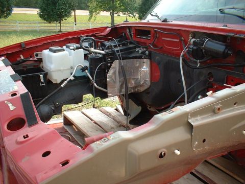 1999 Ford Ranger - The engine bay of a red truck is shown with some components removed, revealing the internal structure and wiring.