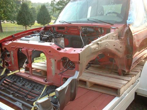 1999 Ford Ranger - The front end of a red truck is disassembled and loaded onto pallets on a trailer.