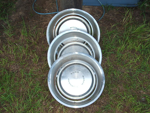 Stack of three Ford hubcaps with 'MOTOR' and 'FORD' visible