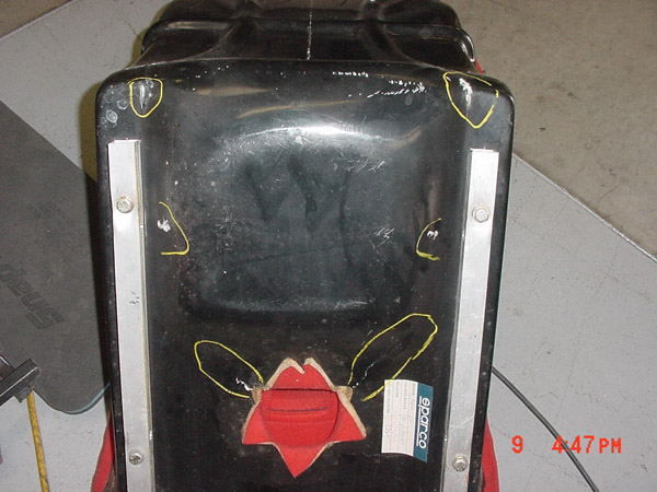 Bottom of a black racing seat with red accents and a Sparco label. Yellow circles highlight areas