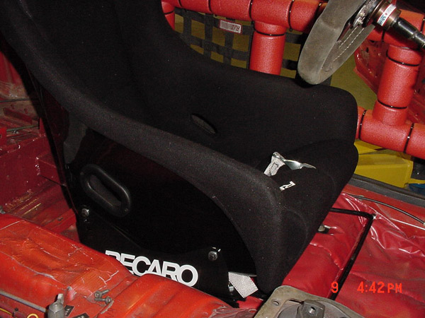 racing seat with RECARO logo, roll cage, and steering wheel inside a car