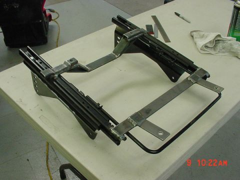 1993 Ford Mustang - A custom-fabricated seat bracket assembly, likely for a vehicle restoration project, sits on a table.