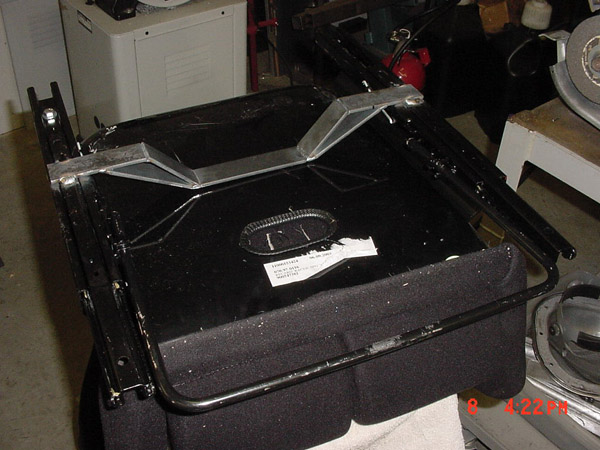 Seat base with metal frame and black fabric cushion. Label visible on top