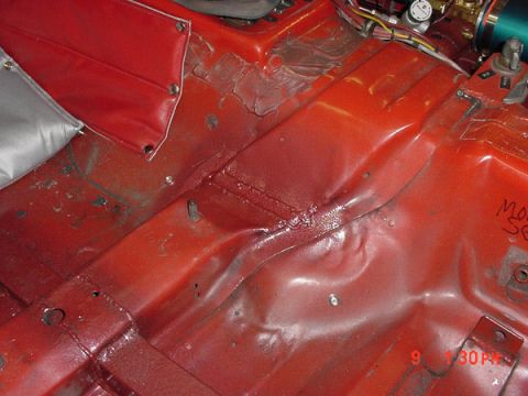 1993 Ford Mustang - The interior floor pan shows signs of damage and repair work, with red upholstery visible in the upper left.