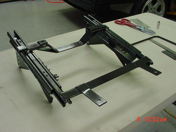 Seat mounting bracket assembly on a table with tools nearby