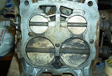 1986 Ford Bronco - Close-up view of a carburetor's throttle plates, showing signs of wear and carbon buildup.