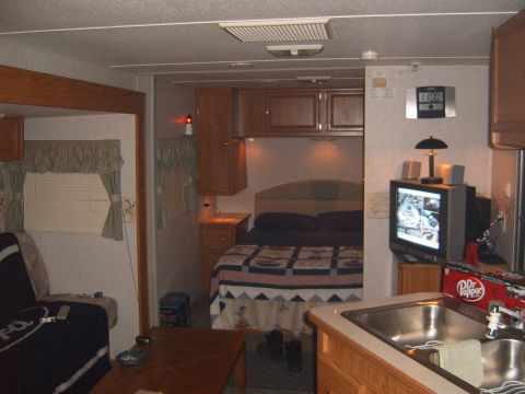 1993 Ford Bronco - The interior of a camper shows a bed, a sink, and a television mounted on the wall.