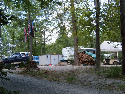 1993 Ford Bronco - A dark blue Ford Bronco is parked in a wooded area next to a camper and storage shed.