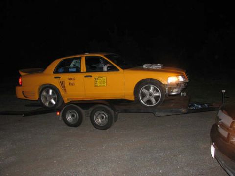 2001 Mercury Grand Marquis - Yellow taxi with custom hood scoop and aftermarket wheels is loaded onto a trailer at night.