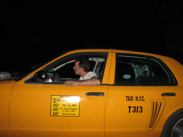 Yellow taxi cab with a driver inside, side view. Shows taxi fare details and N.Y.C. T313 markings
