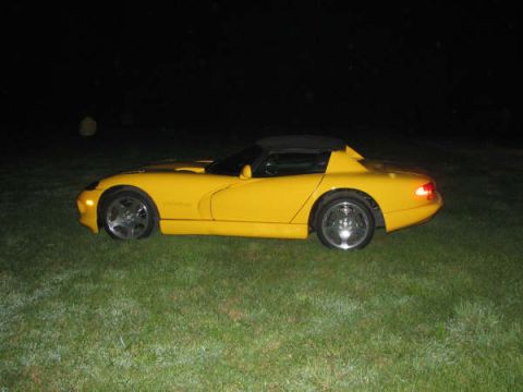 2001 Mercury Grand Marquis - A yellow convertible sports car is seen from the side, parked on a grassy area in the dark.