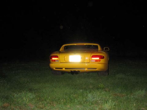 2001 Mercury Grand Marquis - A yellow sports car is parked on a grassy area at night, with its taillights illuminated.