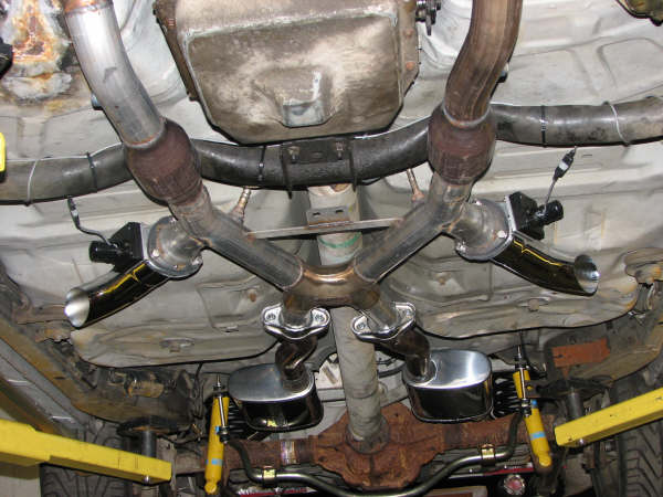 Underside of a car showing the exhaust pipes, mufflers, and catalytic converter