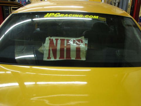 2001 Mercury Grand Marquis - Rear view of a yellow car a JPCACING.COM decal and an NHT sticker on the back window.