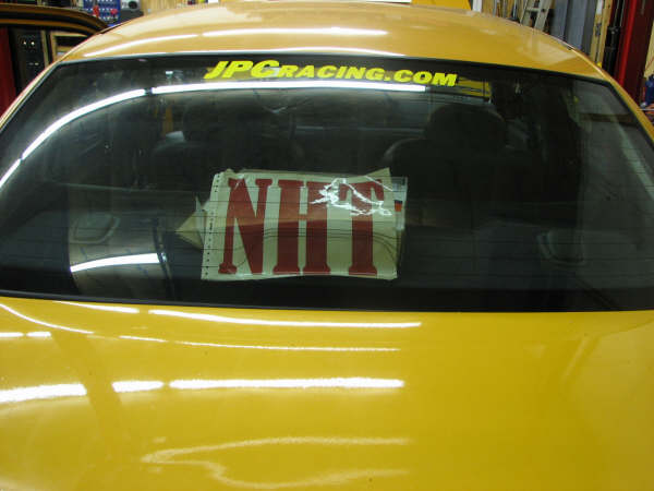 Yellow car rear window with JPCACING.COM and NHT stickers
