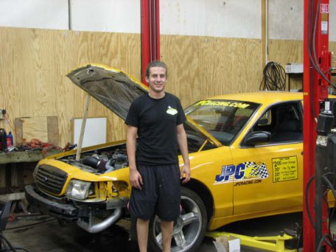 2001 Mercury Grand Marquis - Man stands next to a yellow 2001 Mercury Grand Marquis with its hood open in a workshop.