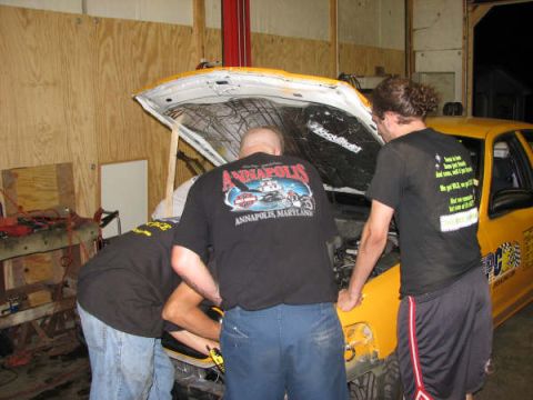 2001 Mercury Grand Marquis - Three people are working on the engine of a yellow taxi cab in a garage.