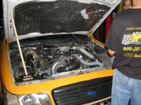 2001 Mercury Grand Marquis - The engine bay of a yellow vehicle is open, revealing a turbocharger and custom intake system.
