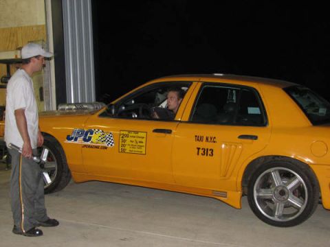 2001 Mercury Grand Marquis - A man stands next to a yellow taxi with racing decals and custom wheels.
