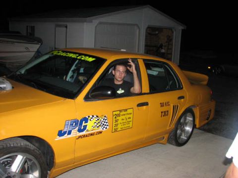 2001 Mercury Grand Marquis - A yellow taxi cab, identified as a 2001 Mercury Grand Marquis, is parked outside a garage at night.