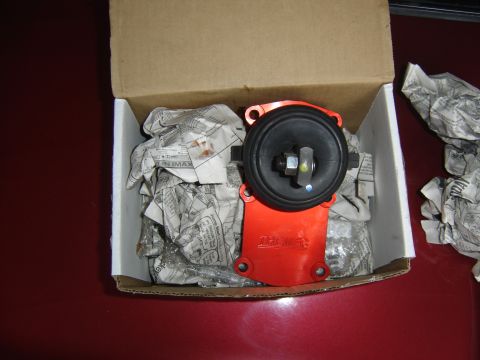 1988 Ford Bronco - An orange and black automotive part is shown inside a cardboard box, cushioned by crumpled newspaper.