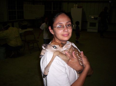 1986 Ford Bronco - A woman holds a young fawn, which rests on her shoulder. Other people are visible in the background.