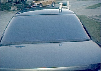 1994 Ford Taurus - A dark car's roof and windshield are shown, with a tan vehicle in the background.