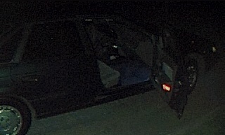 1994 Ford Taurus - A dark sedan is seen from the side with the driver's door ajar, revealing the interior.