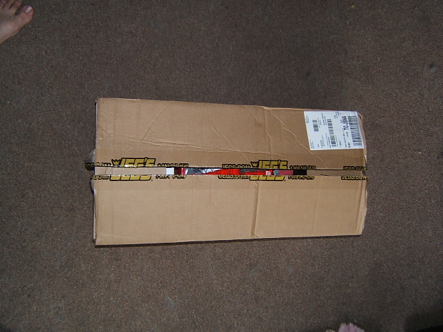 Cardboard box with JEFF'S.COM tape, on carpet. A shipping label is visible on the top right