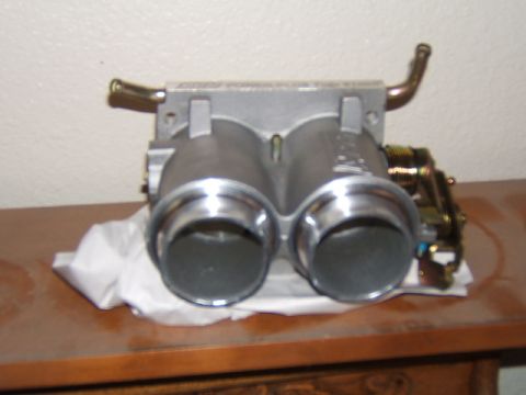 1988 Ford Bronco - A dual throttle body part is shown on a wooden table, likely for an automotive installation.