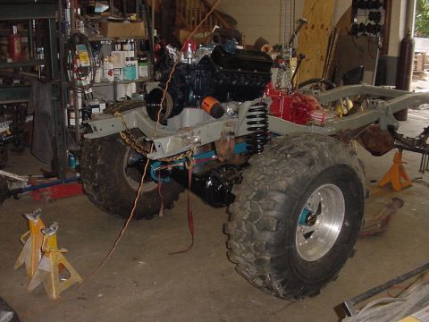 1969 Ford Bronco - A vehicle chassis is undergoing repairs or modifications in a workshop setting, with the engine and large tires installed.