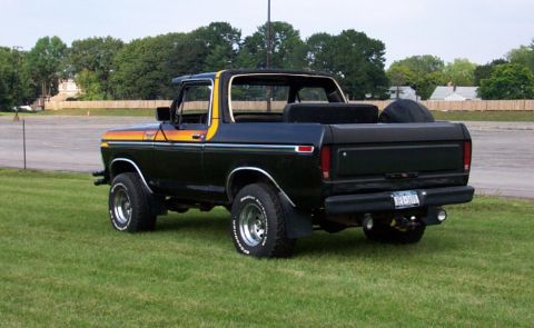 1979 Ford Bronco - This Ford Bronco is parked on grass with trees and a building in the background.
