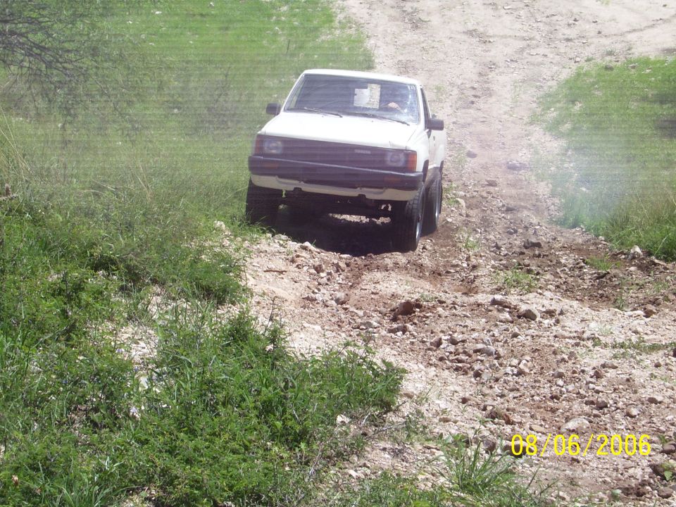 White Toyota pickup truck driving down a rocky off-road trail, front view, dated 08/06/2006