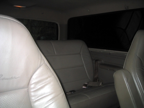 1996 Ford Bronco - The interior of a vehicle shows the rear seating area with leather seats and a sunshade on the window.