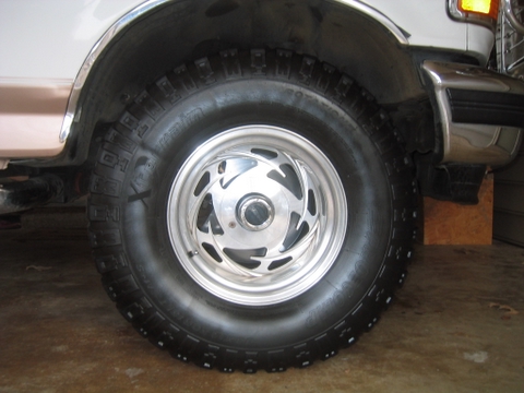 1996 Ford Bronco - Close-up of the front wheel and fender of a 1996 Ford Bronco, showing chrome trim and a distinctive wheel design.