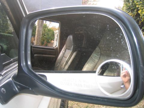1996 Ford Bronco - View of the vehicle's interior, including leather seats, captured in the side mirror.
