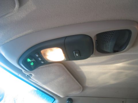 1996 Ford Bronco - Interior shot looking up at a gray overhead console mounted in a tan headliner, with the dome light illuminated, a green digital compass an…