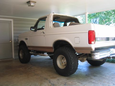 1996 Ford Bronco - Three-quarter rear view of a white full-size Ford Bronco with tan lower two-tone stripe and the removable hardtop rear section taken off, p…