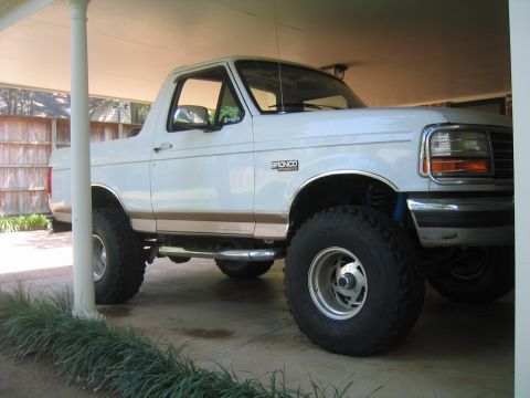 1996 Ford Bronco - Low three-quarter front view from the passenger side of a white full-size Ford Bronco with the rear top removed, showing the Bronco fender…
