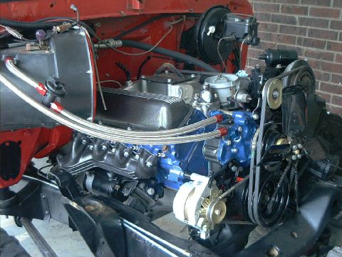 1978 Ford Bronco - Ford-blue V8 mounted in a stripped red engine bay, topped with a polished aluminum intake and carburetor, black valve covers and cast exhau…