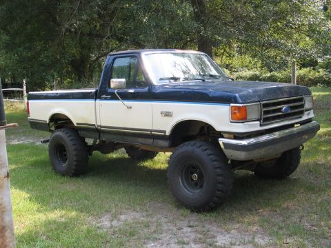 1989 Ford F-150 - This lifted pickup truck has a two-tone paint scheme and sits high on large off-road tires.